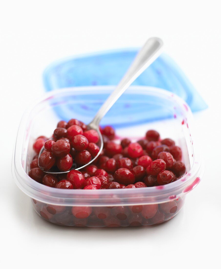 Gekochte Cranberries mit Löffel in einer Plastikdose