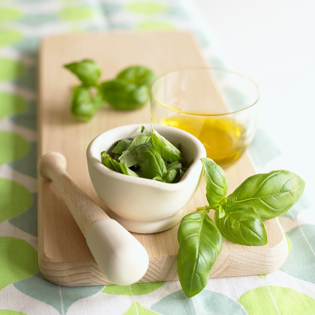 Fresh basil leaves in a mortar and olive oil
