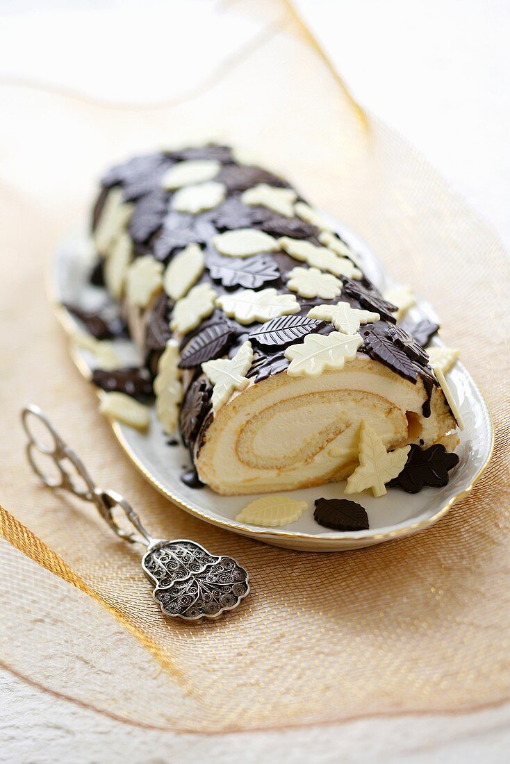 Sponge roll decorated with white and dark chocolate leaves