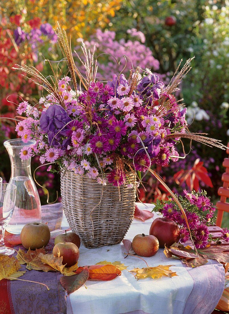 Arrangement of Michaelmas daisies, apples, autumn leaves on table