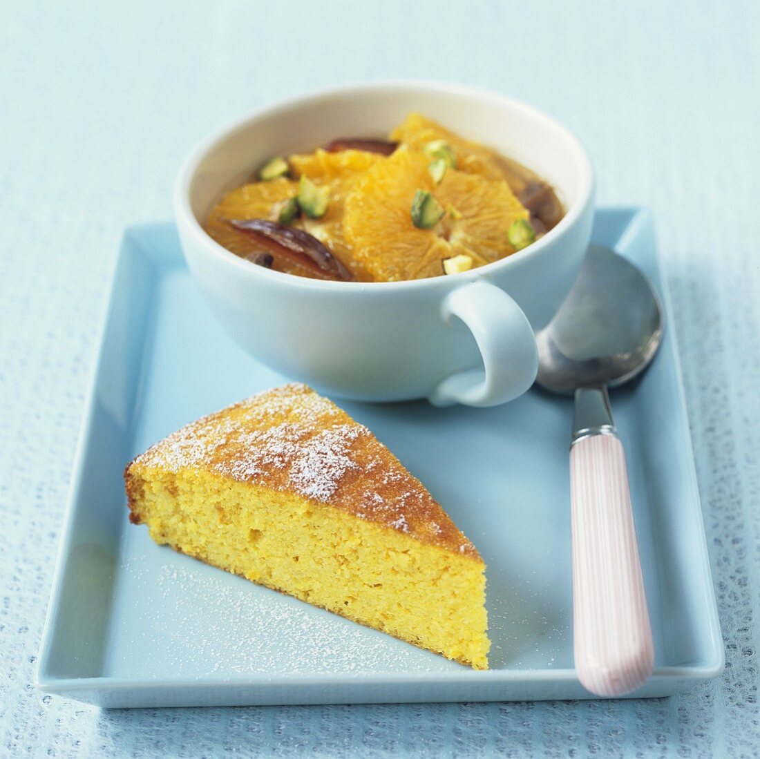 Ein Stück Orangenkuchen und Orangensalat mit Pistazien