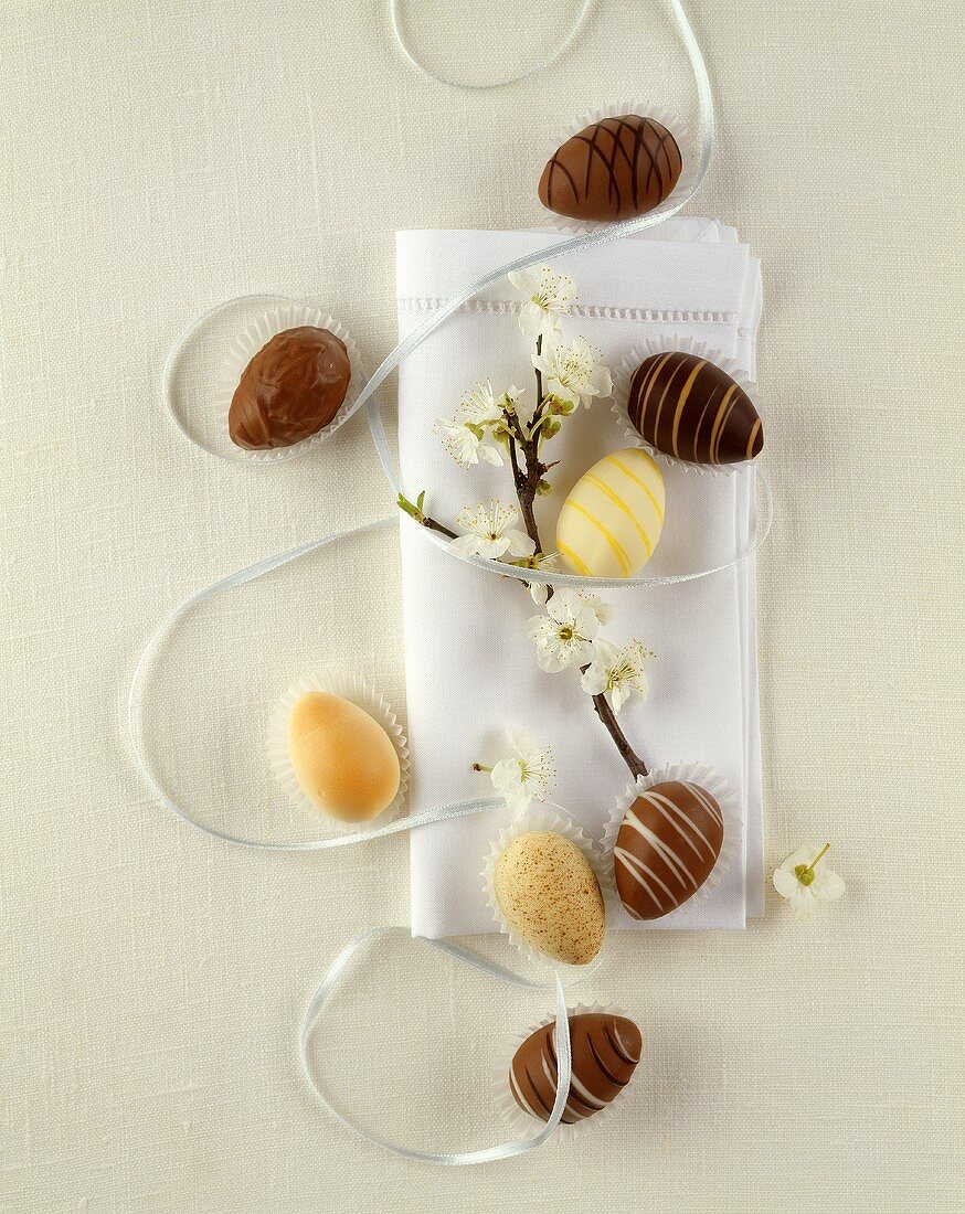Schokoladenostereier und weiße Serviette mit blühendem Zweig