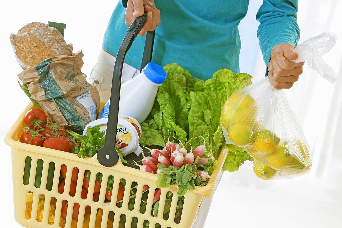 Woman holding a shopping basket full of fresh products