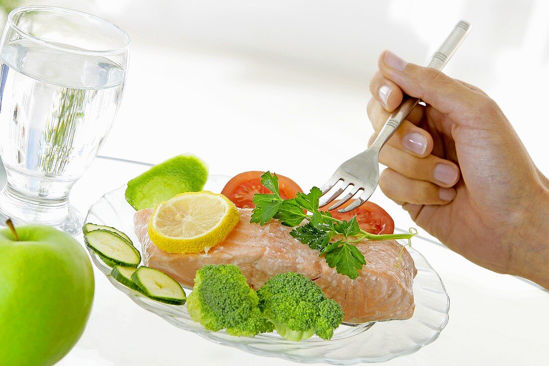 Salmon fillet with vegetables, a glass of water & an apple