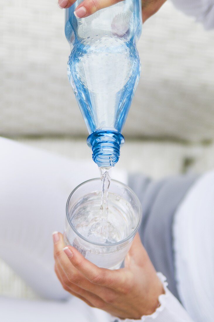 Mineralwasser ins Glas einschenken