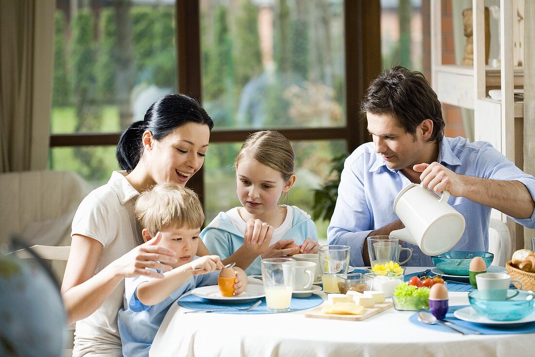 Familie sitzt mit zwei Kindern am Frühstückstisch