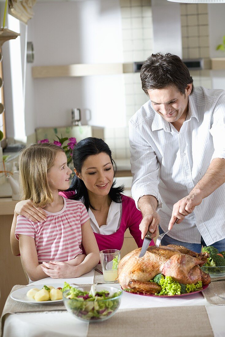 Man carving roast turkey for the family