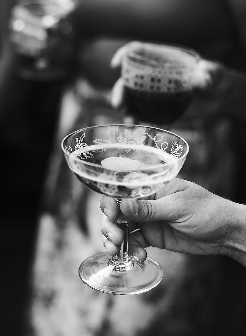 Hand hält ein Glas Champagner