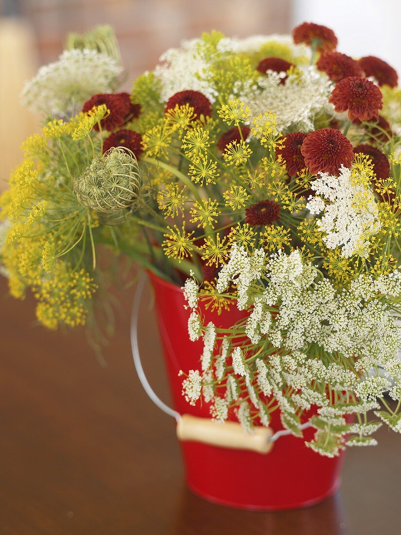 Bunch of flowers (including dill flowers) in a red bucket