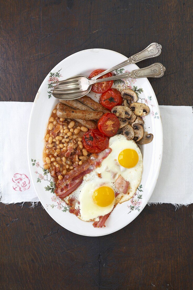 Englisches Frühstück mit Baked Beans, Spiegelei, Bratwurst