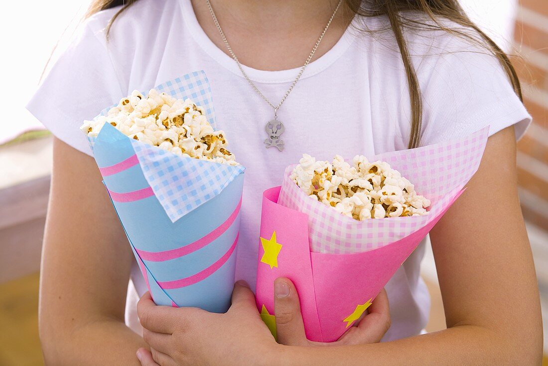 Mädchen hält zwei Tüten Popcorn