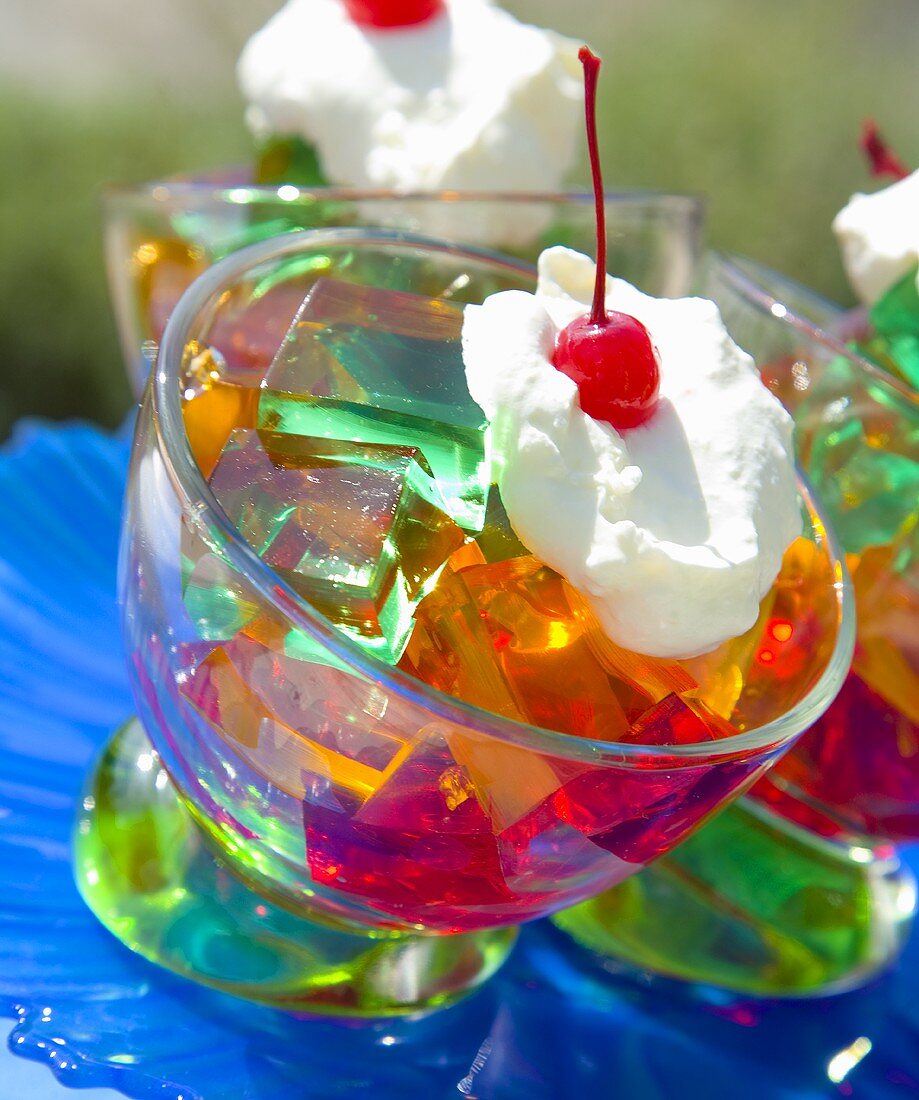 Cubes of coloured jelly with cream and cocktail cherry