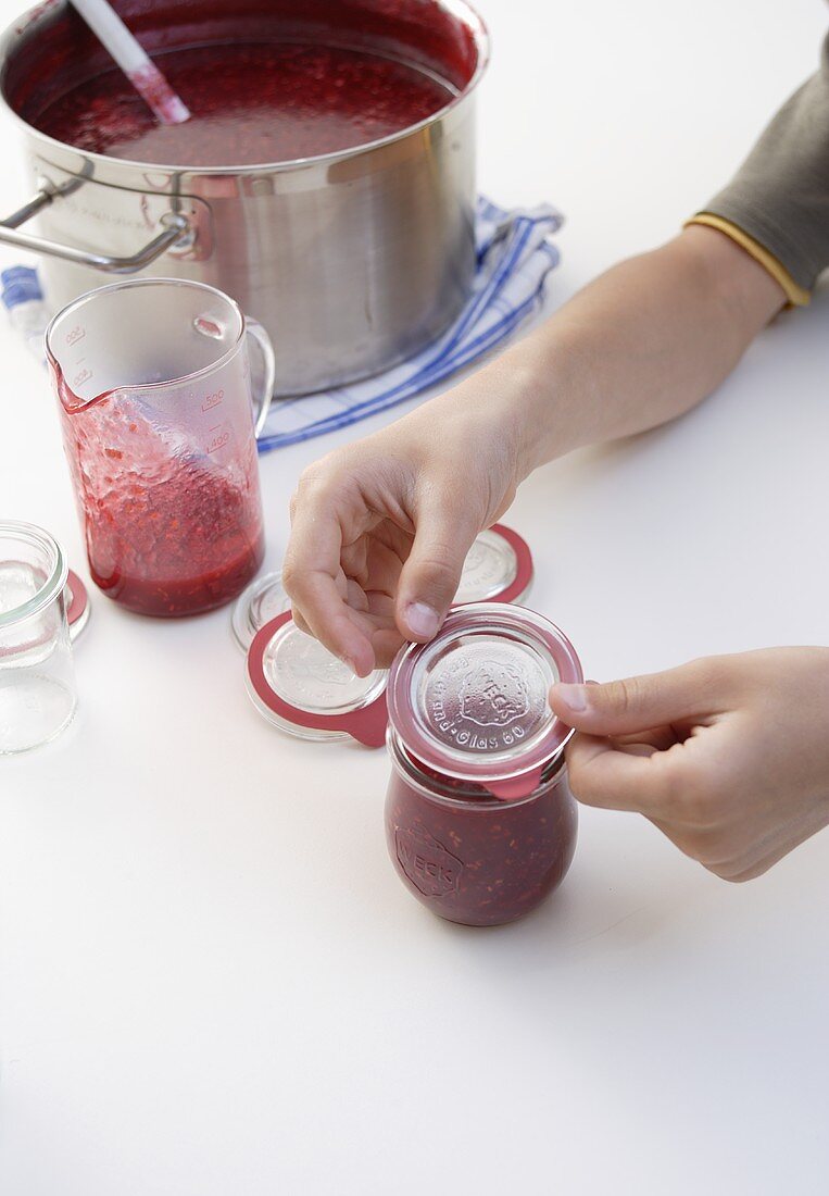 Einmachglas mit Himbeermarmelade verschliessen