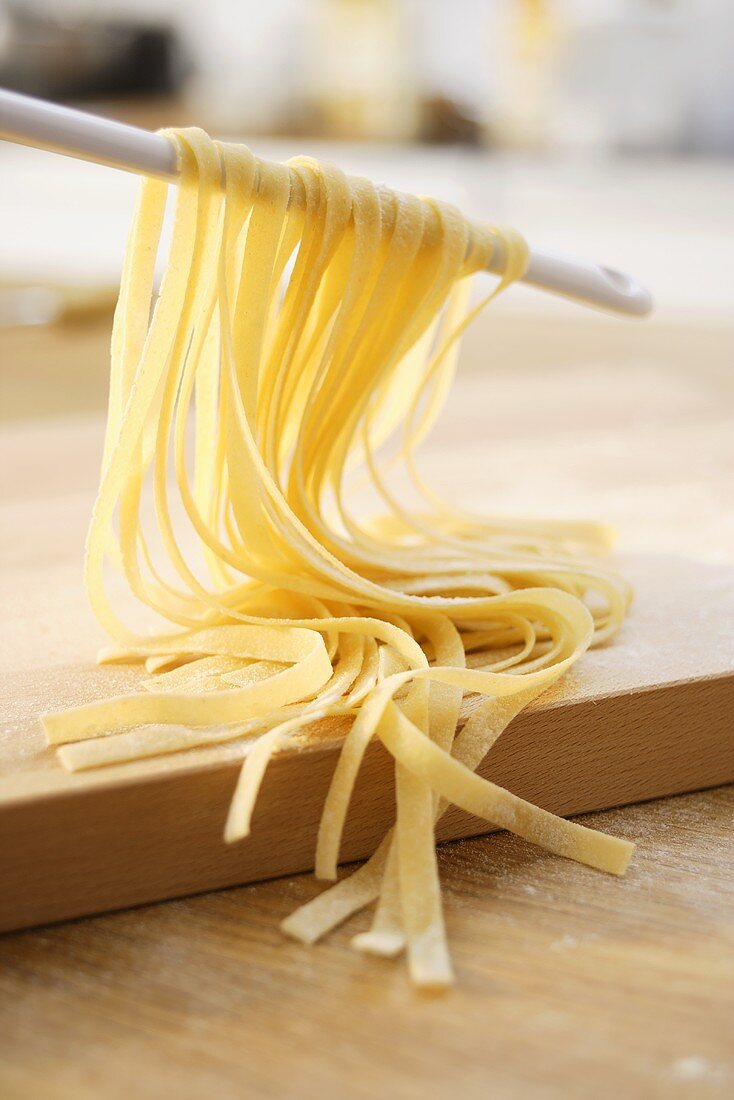 Home-made ribbon pasta hanging over a kitchen spoon