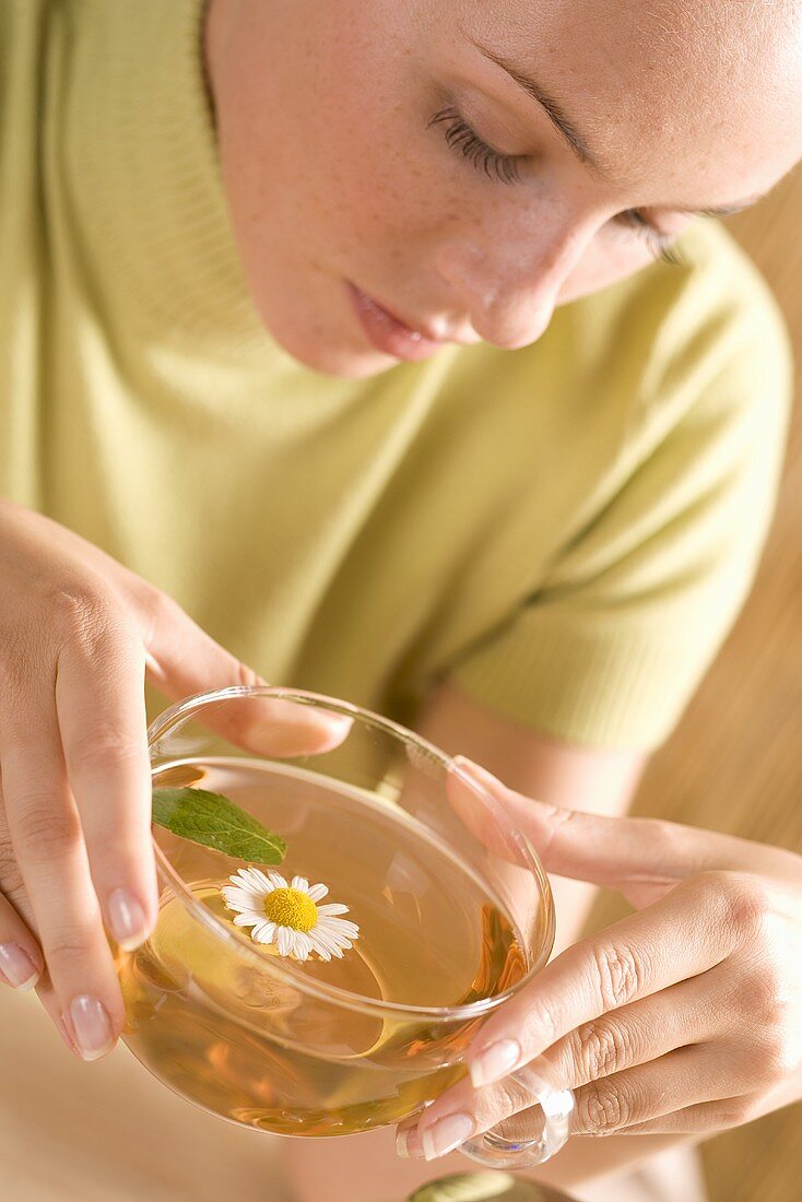 Young woman drinking chamomile tea