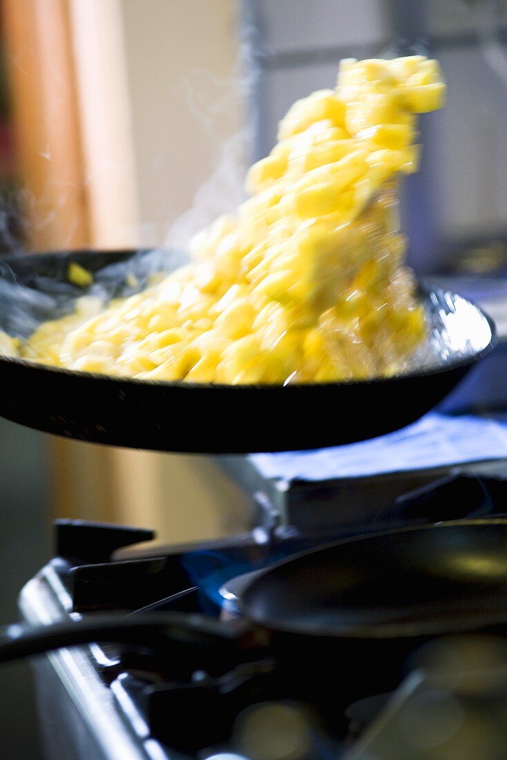 Food being tossed in a frying pan