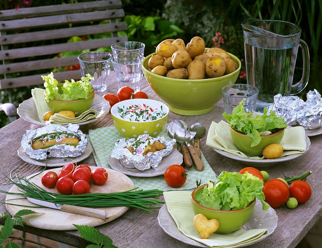 Potatoes, herb quark, tomatoes and lettuce on laid table