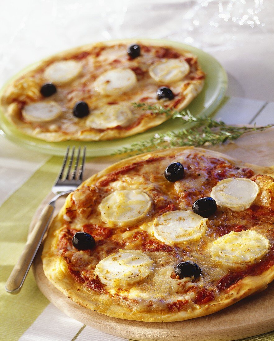 Pizzas topped with goat's cheese and black olives