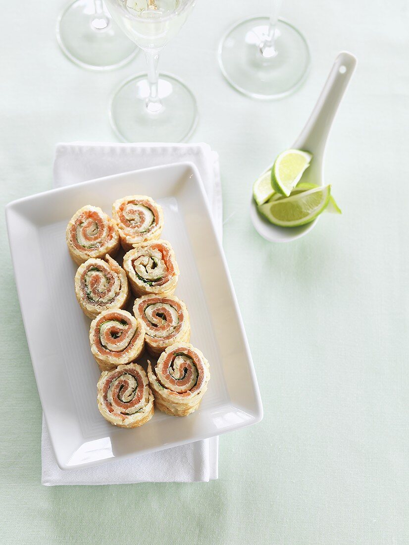 Pancake rolls filled with smoked salmon, lime wedges