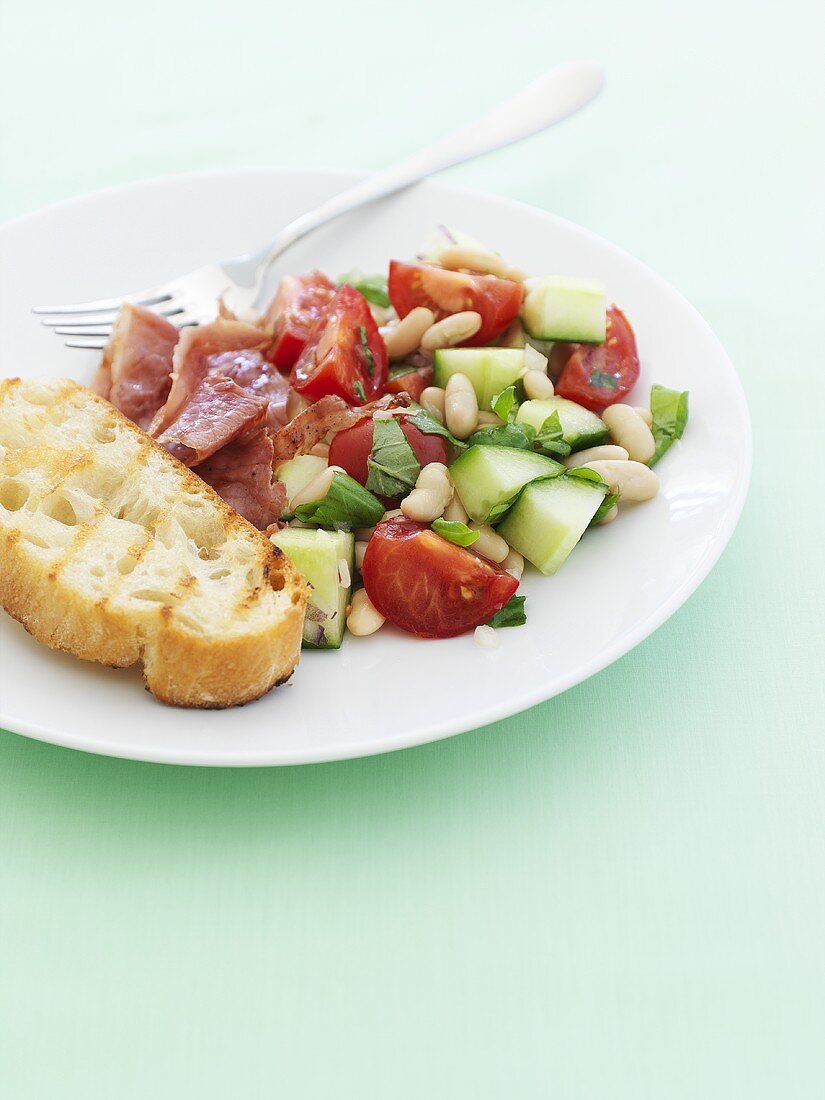 Summer vegetable salad with fried ham and white bread