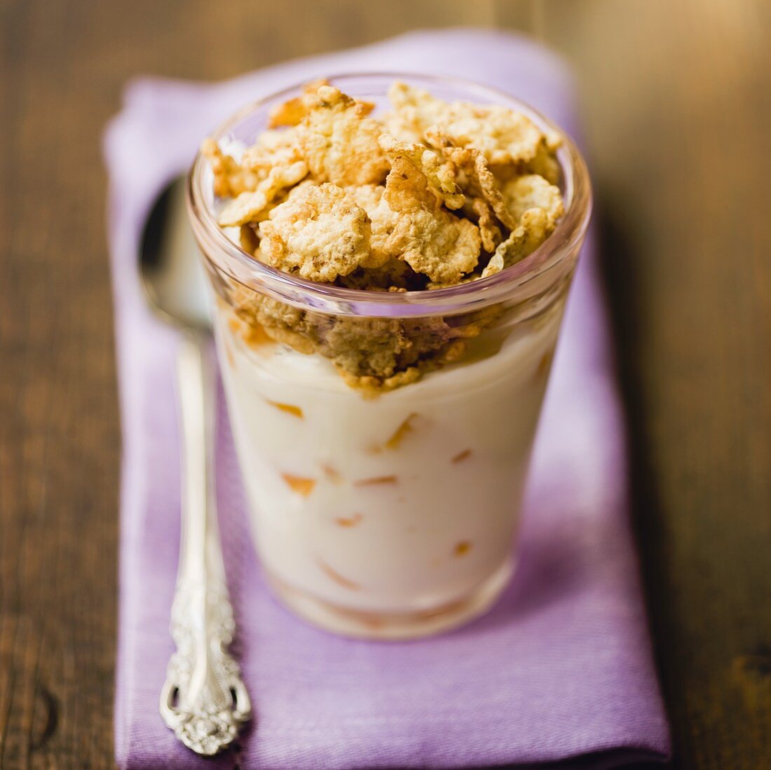 Yoghurt with peach and wholemeal cornflakes in a glass