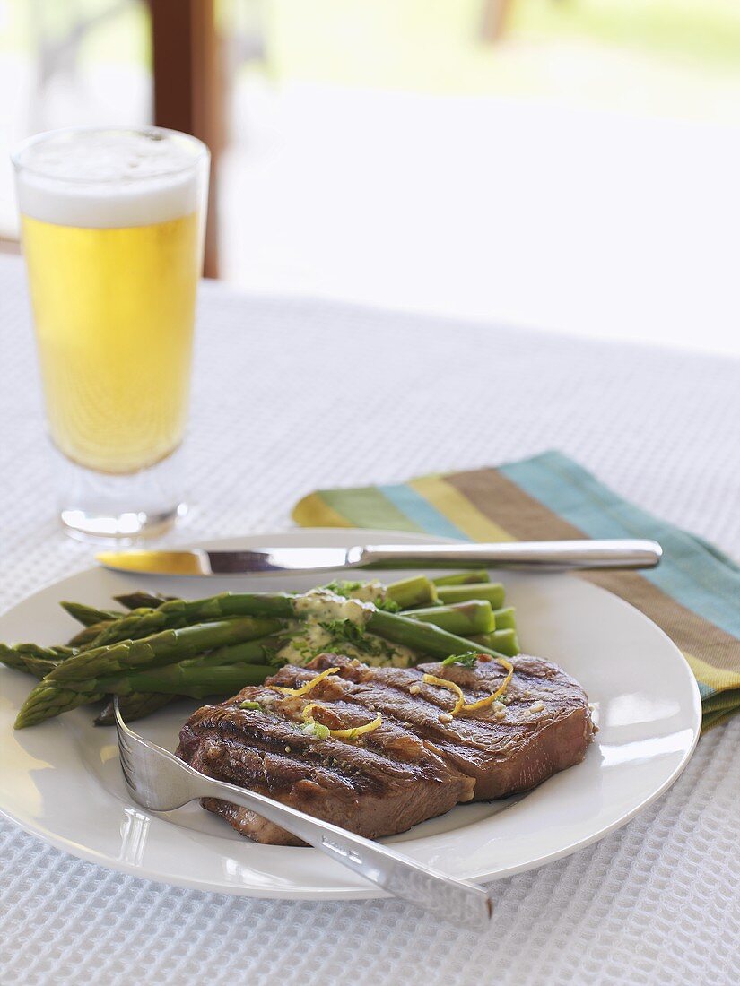 Grilled beef steak, green asparagus and beer