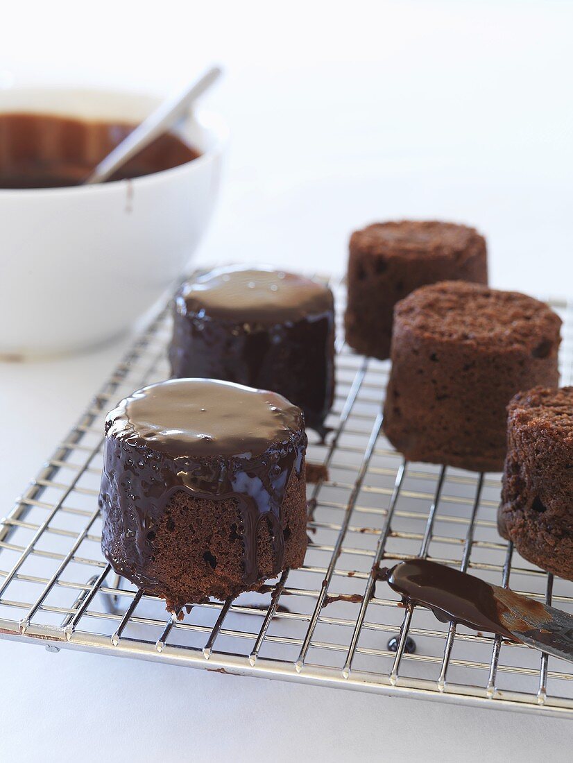 Covering small chocolate cakes with chocolate icing