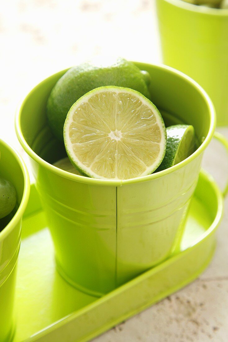 Whole and halved limes in a green beaker