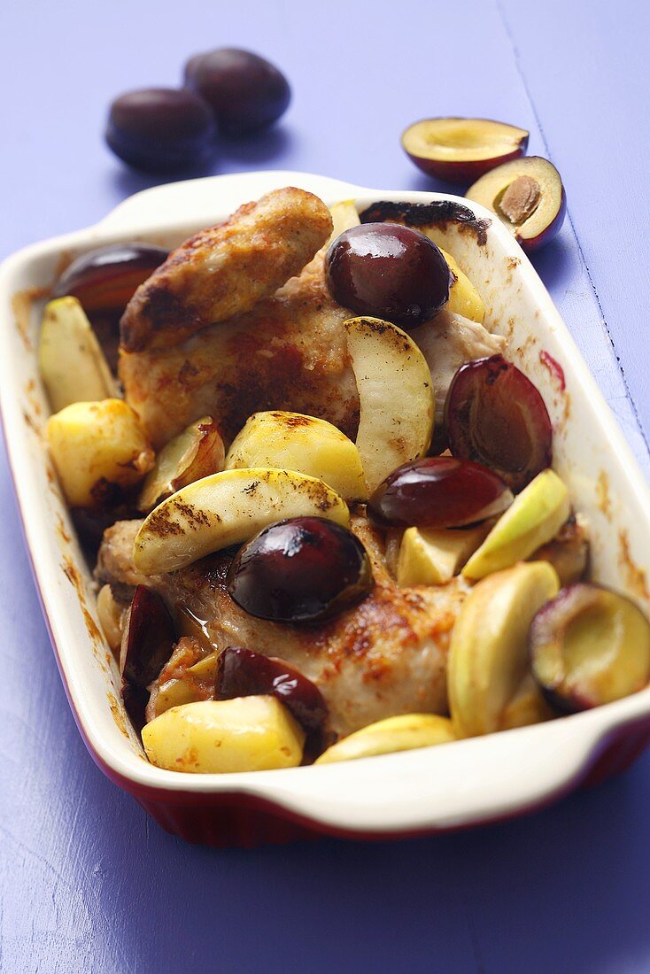 Chicken with apples and plums in roasting dish