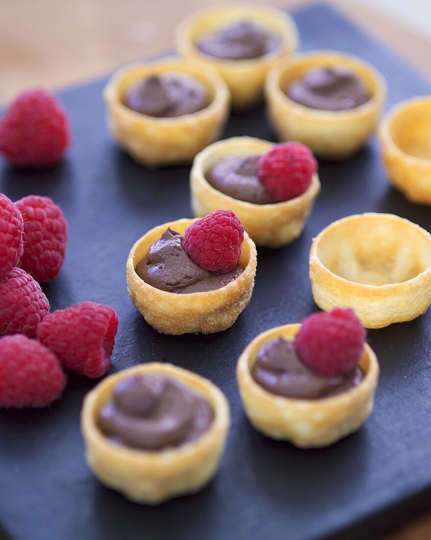 Several pastry shells filled with chocolate mousse & raspberries