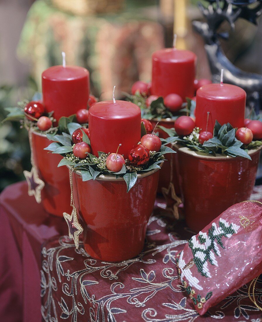 Vier rote Stumpenkerzen mit Weihnachtsschmuck