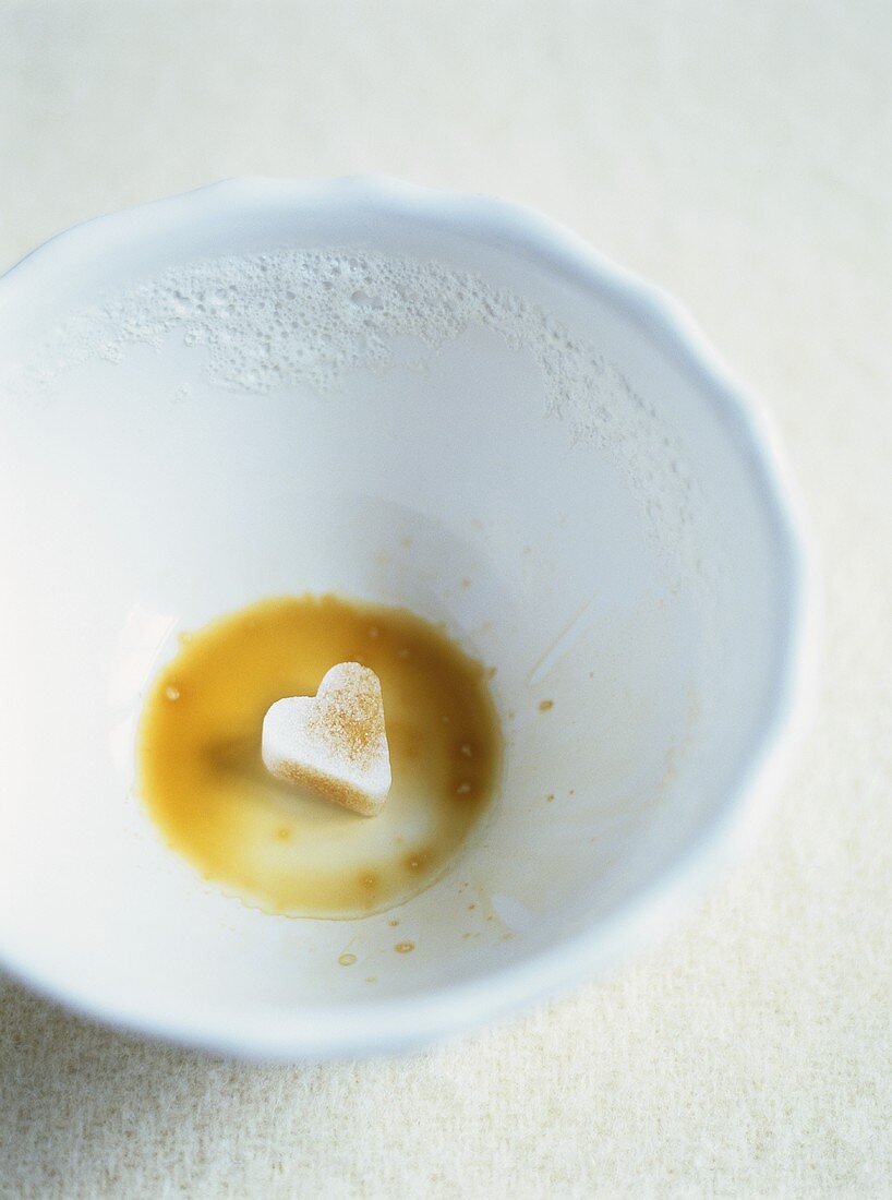 Reste von Café au lait mit herzförmigem Zucker