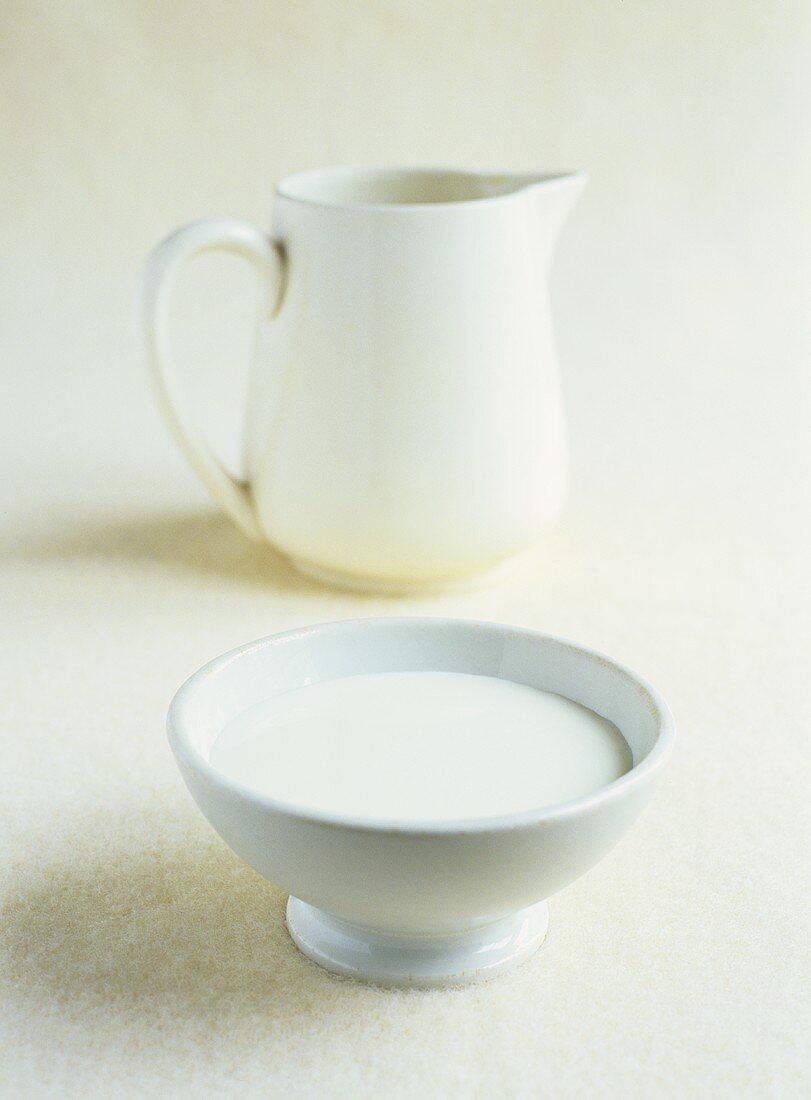A bowl of milk and a milk jug