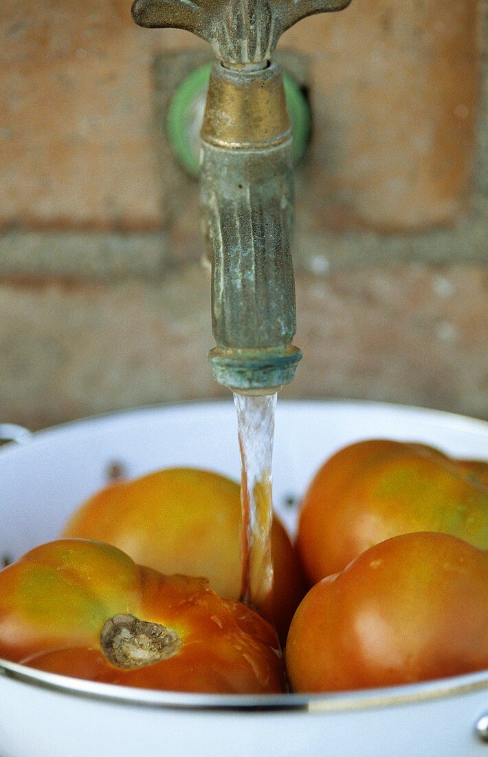 Washing fresh tomatoes under a tap