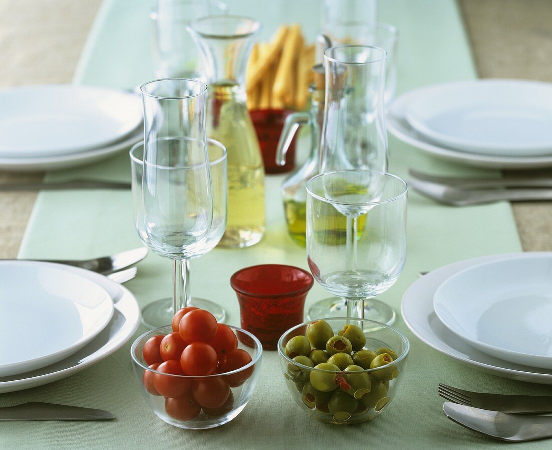 Schälchen mit Tomaten und Oliven auf gedecktem Tisch