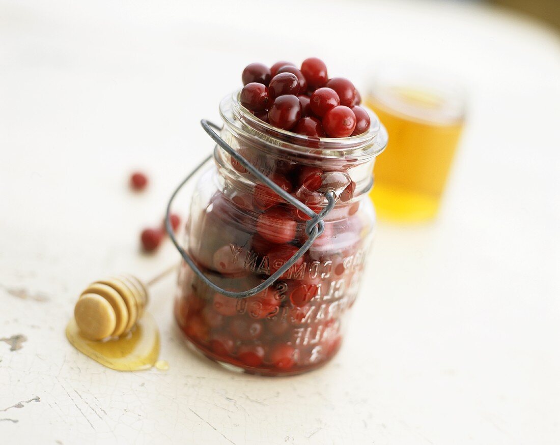 Cranberries in einem Einmachglas und Honig