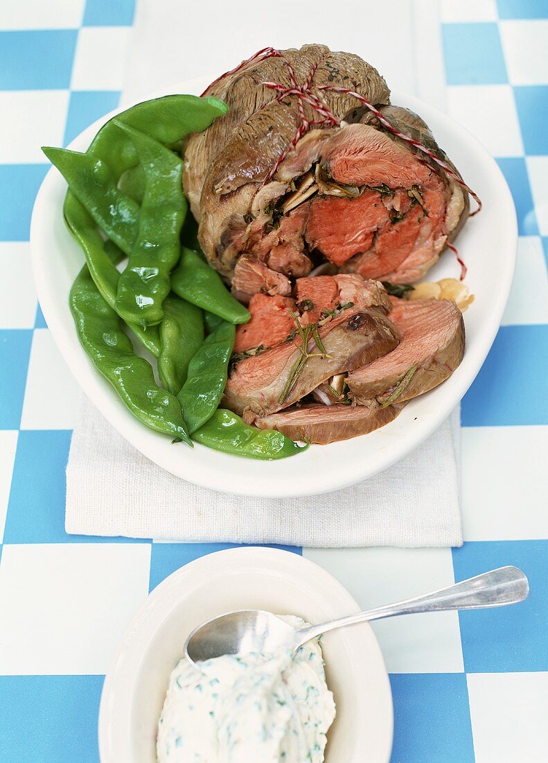 Cooked leg of lamb with garlic sauce and mangetout