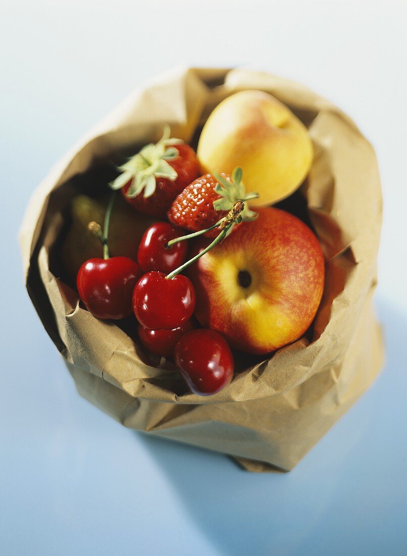 Cherries, apples and strawberries in a paper bag