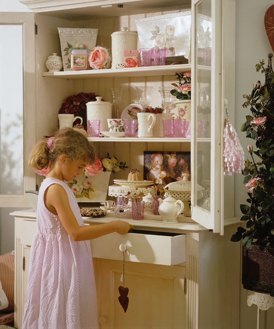 A girl standing in front of a crockery cupboard