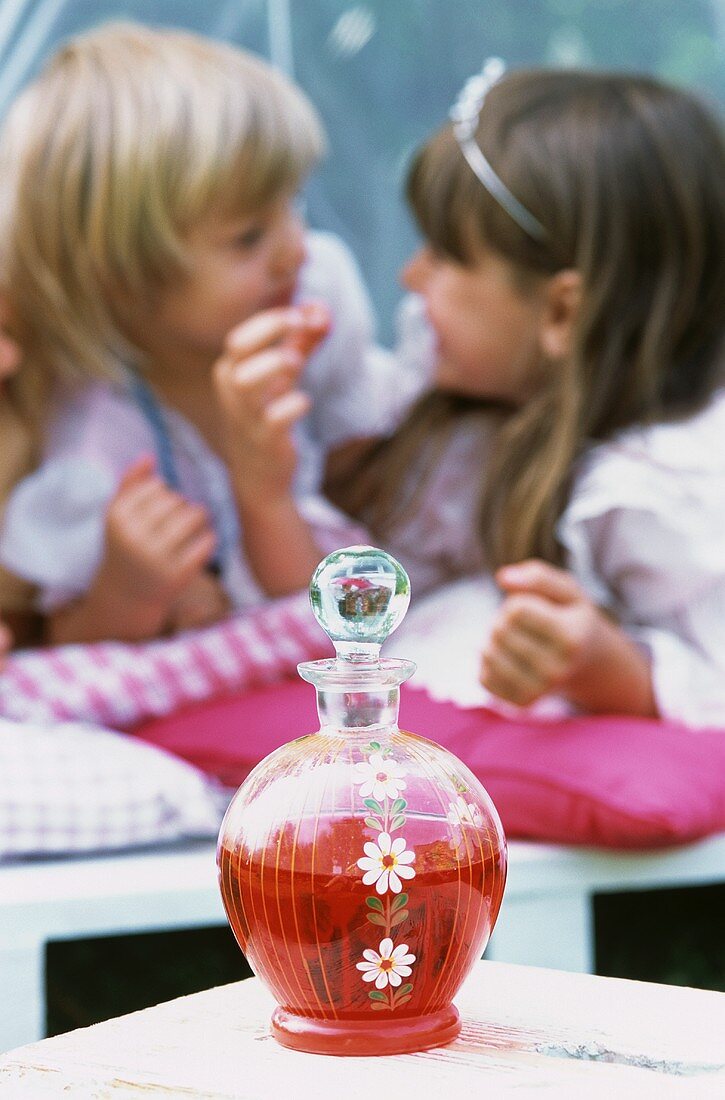 A bottle of strawberry juice with two girls in the background