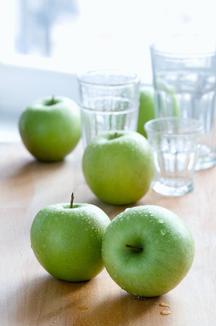Mehrere grüne Äpfel und Trinkgläser