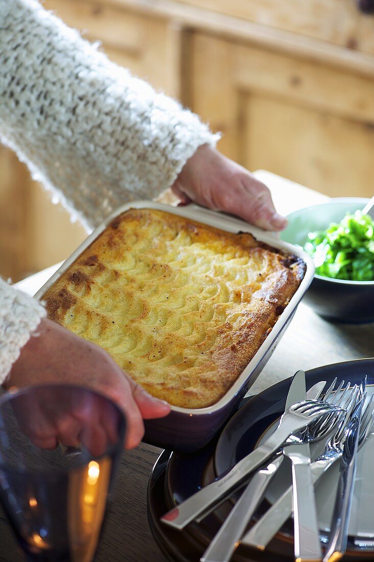 Frau serviert Shepherds Pie