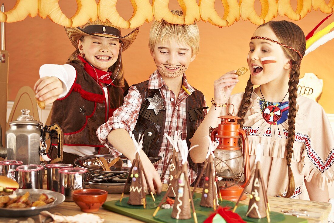 Three children dressed as cowboys and Indians at a party buffet