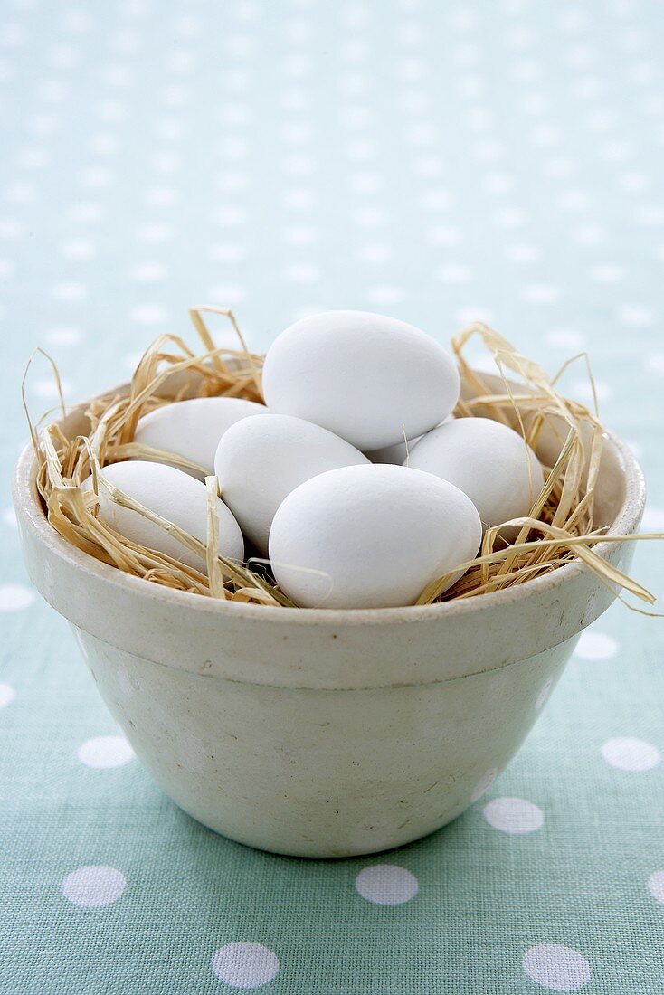 White eggs in a clay pot with straw (Easter)