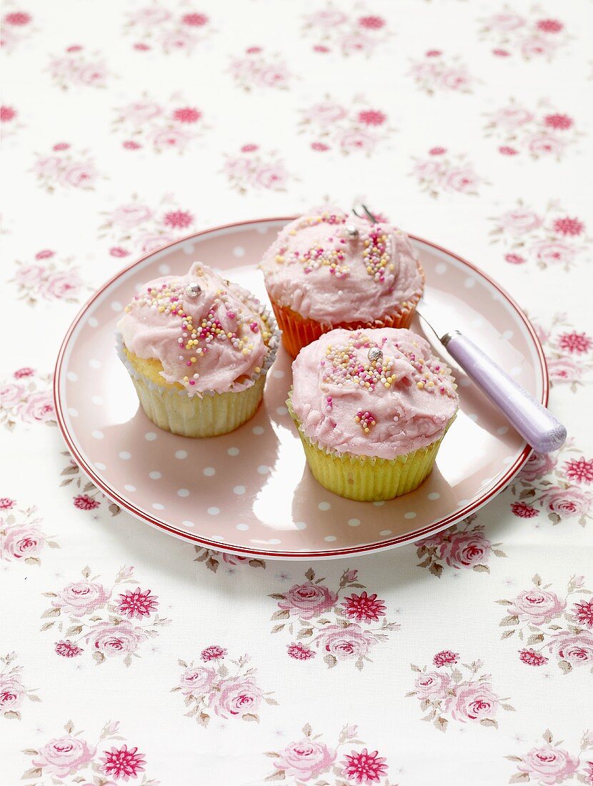 Three pink cupcakes on a polka dot plate