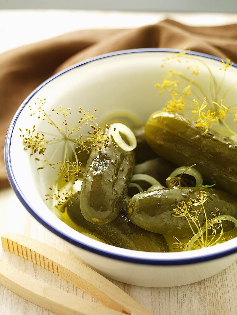 Gherkins with onions and dill in an enamel bowl