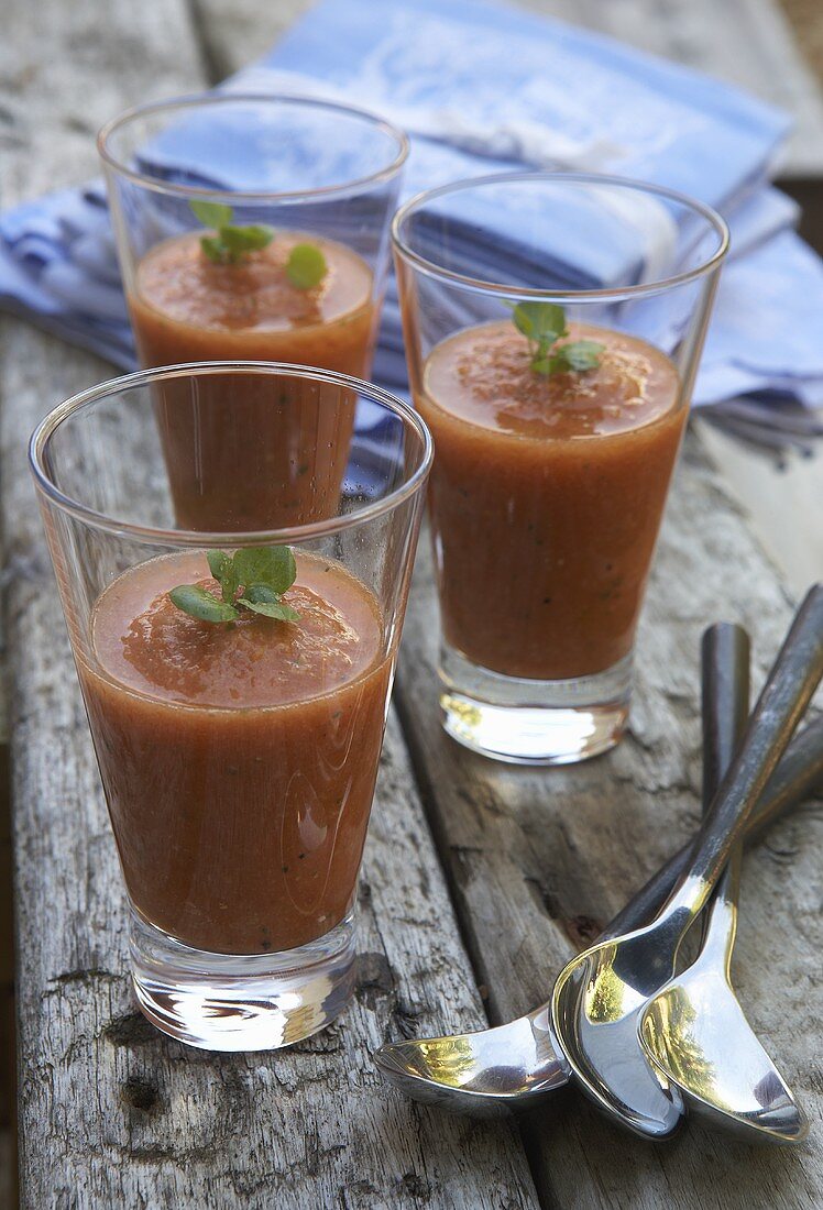 Three glasses of gazpacho on a wooden table
