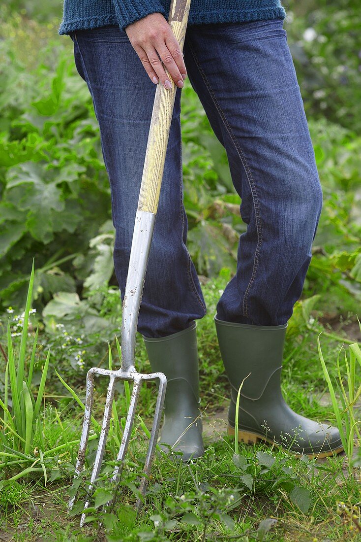 A person in a field with a garden fork