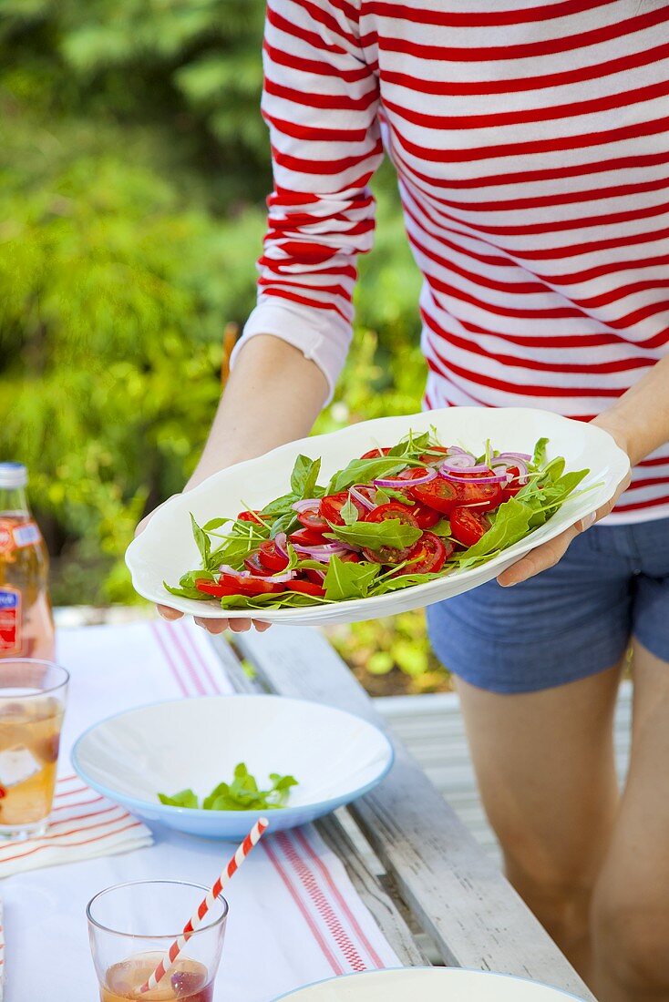 Mädchen hält Teller mit Tomaten-Rucola-Salat