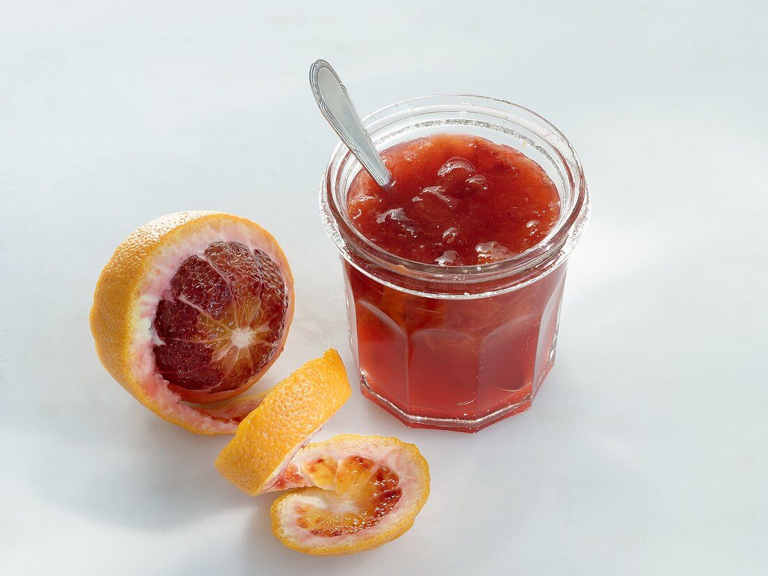 A jar of blood orange marmalade with a blood orange on the side